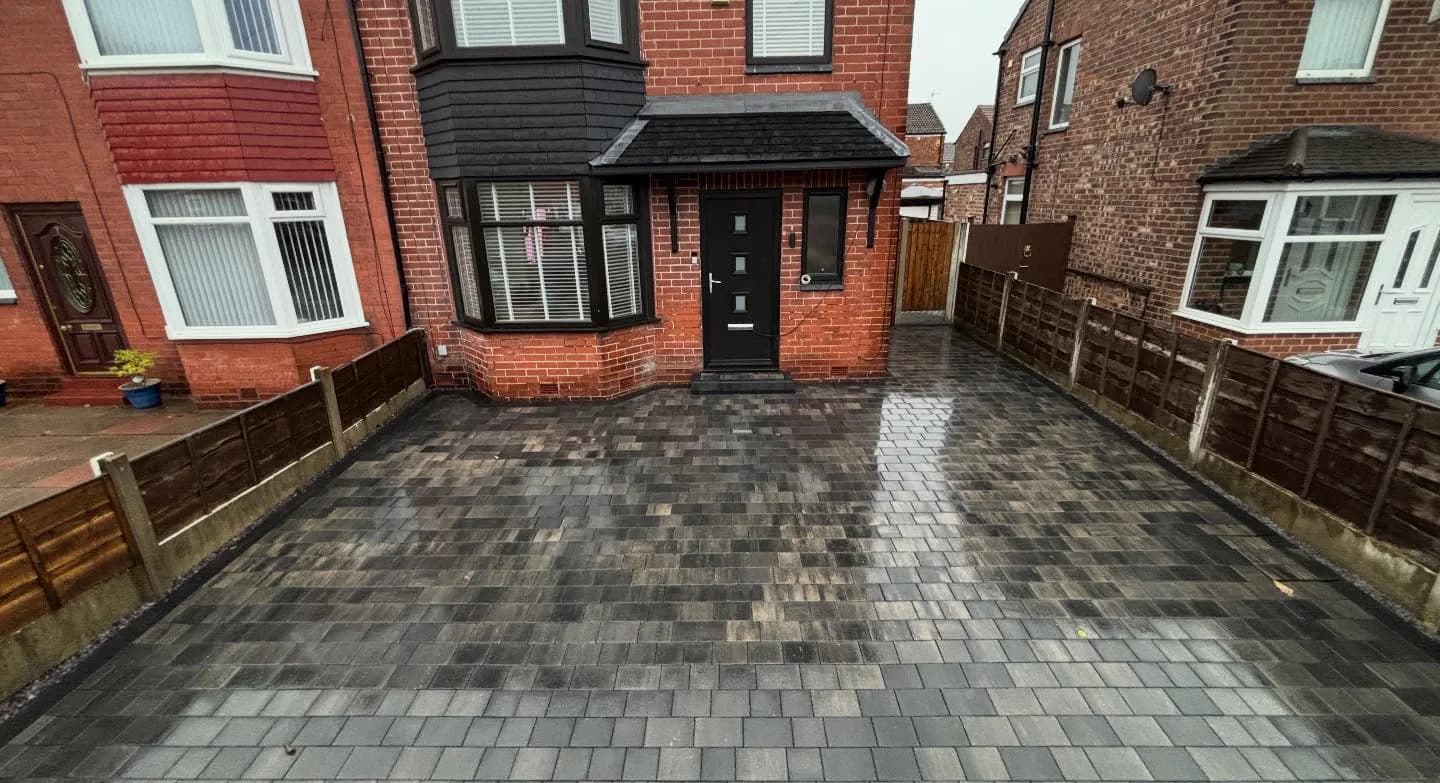 Completed grey block-paved driveway outside a red-brick home