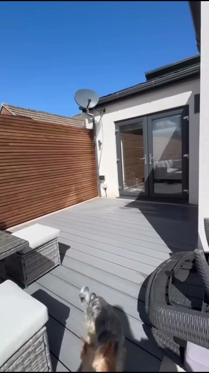 Grey composite decking with outdoor furniture and a horizontal timber boundary screen