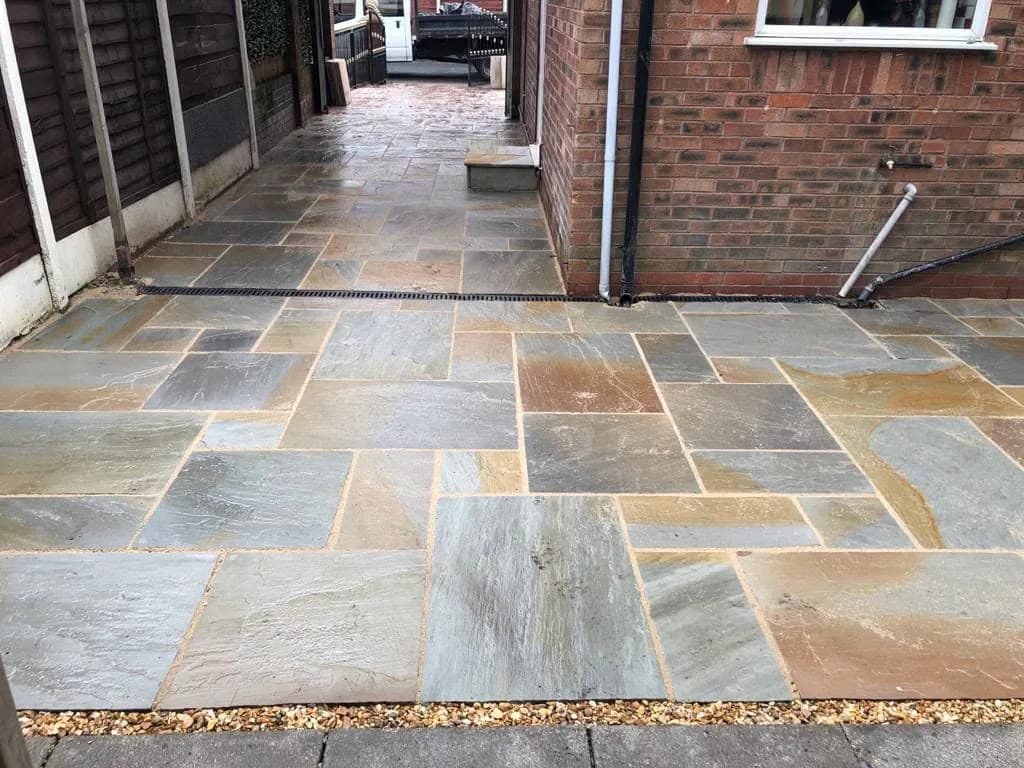 Completed multitone natural stone paving and side path beside a brick house