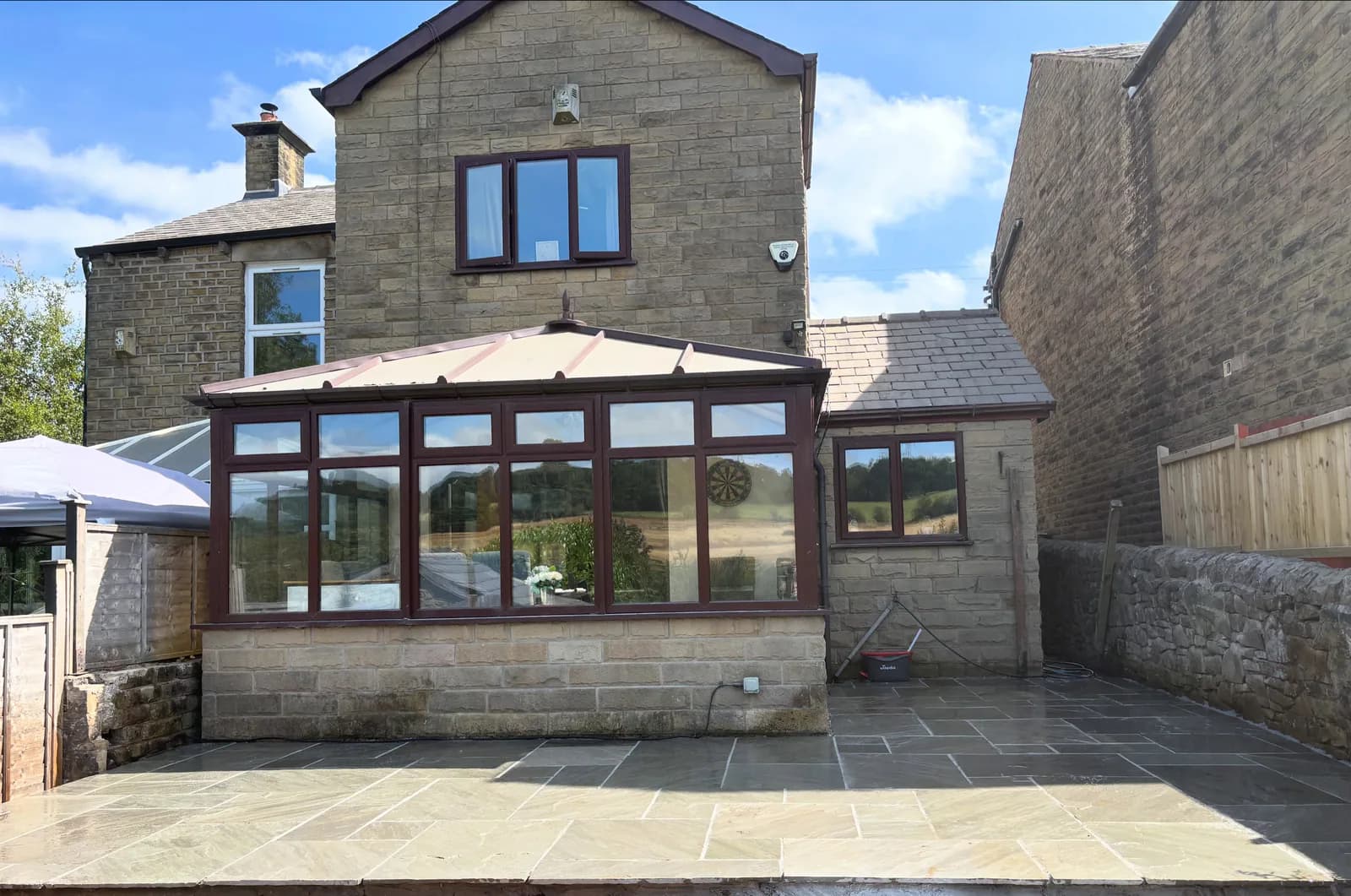 Completed natural stone patio around a conservatory and stone property